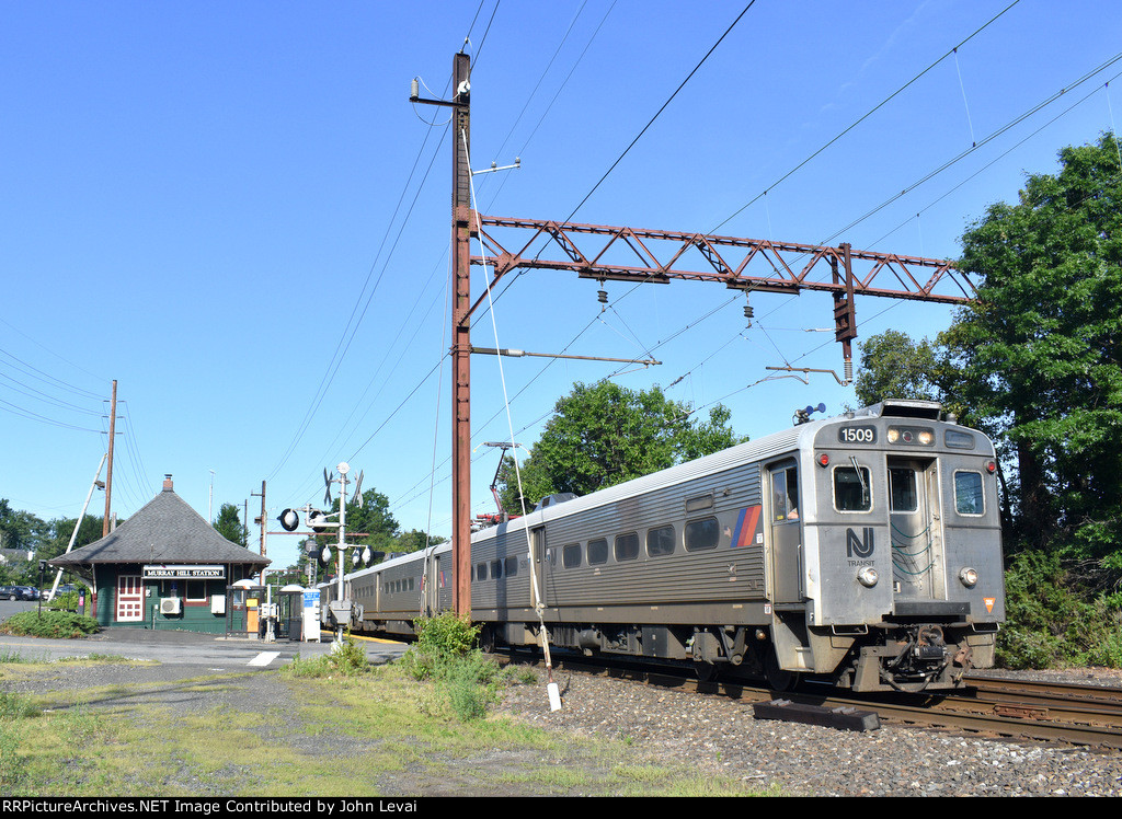 NJT Train # 414, enroute from Gladstone to Hoboken Terminal, departing Murray hill Station and crossing over Foley Place at grade 